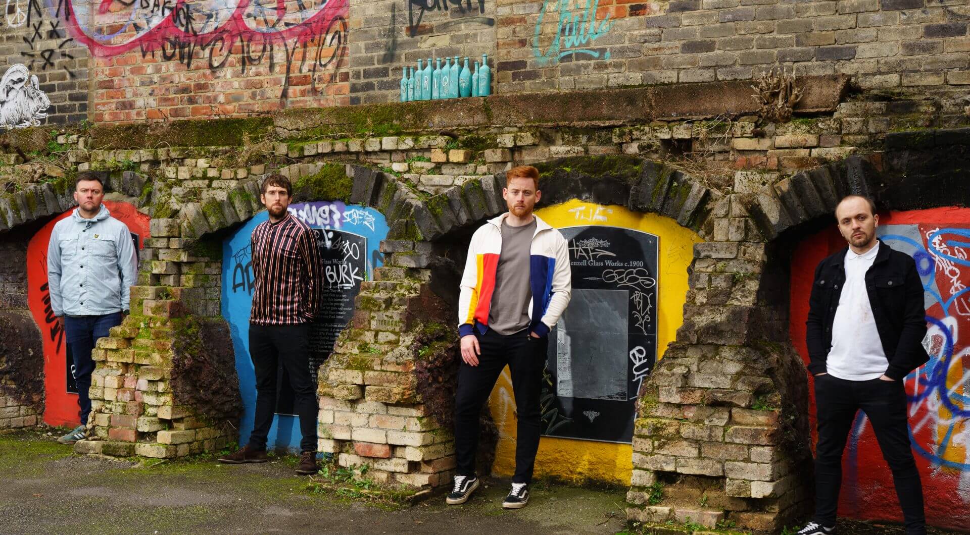 The Jet Reds standing apart infront of a brick structure.