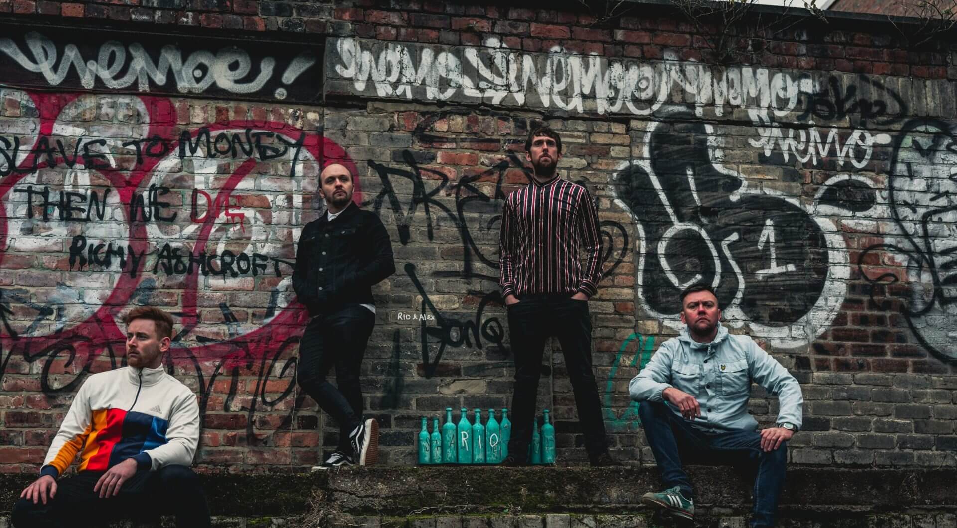 The Jet Reds standing infront of a graffiti covered brick wall.